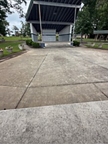 Concrete apron in front of a pavilion before washing, mottled grey across the slab