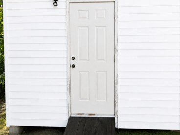 The same outbuilding after washing, door and siding back to white