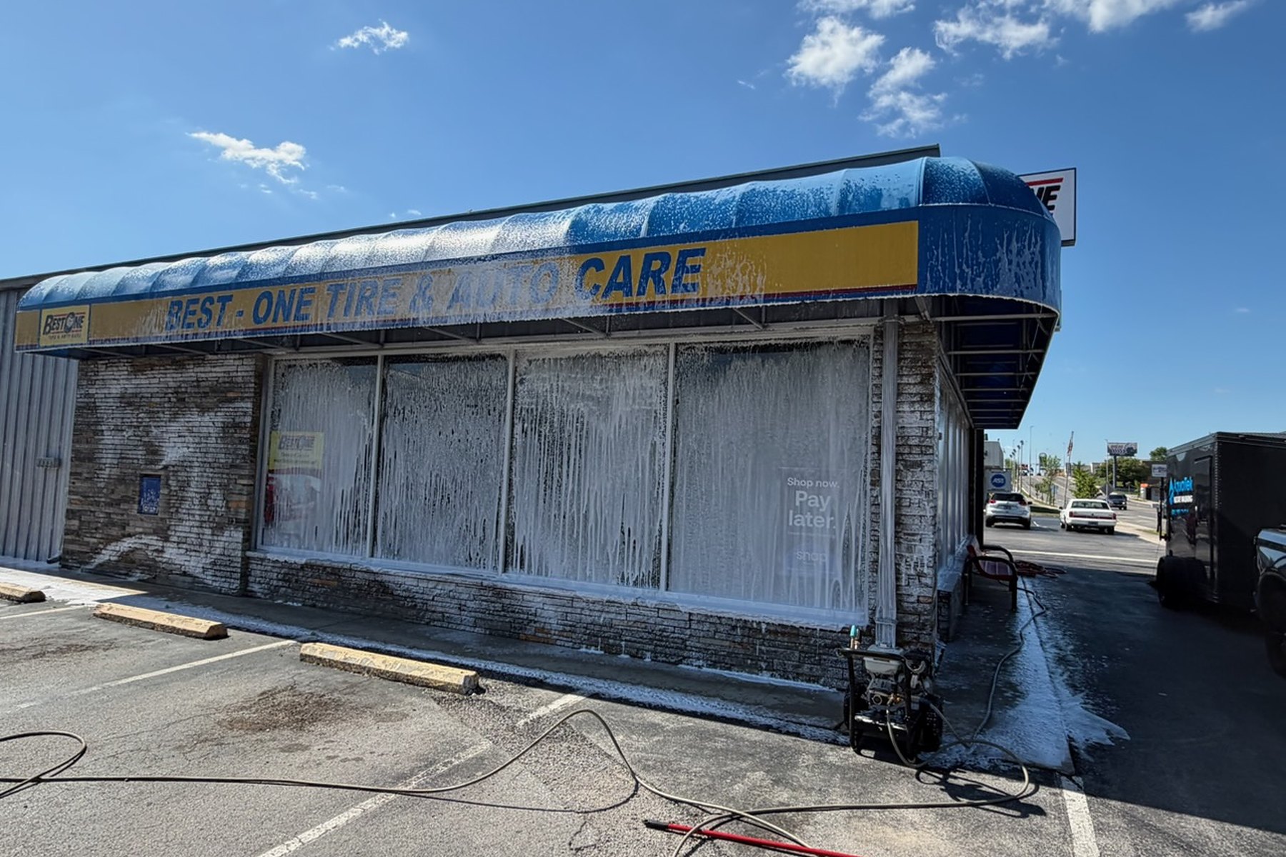 A Crossville storefront mid soft wash, the awning and shopfront windows under a coat of cleaning foam